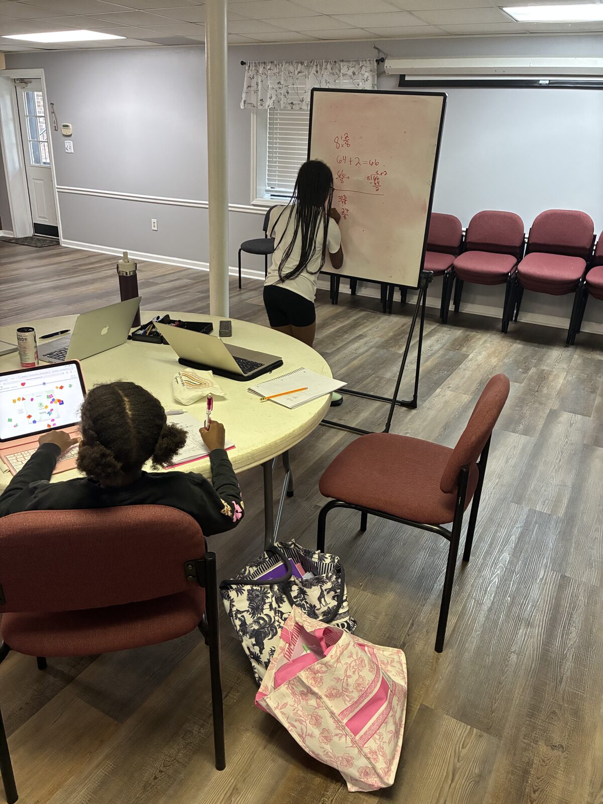 IIA students working through math problems at the whiteboard and on a tablet